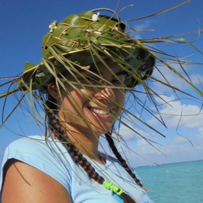 Tumi, shaded by her coconut leaf hat